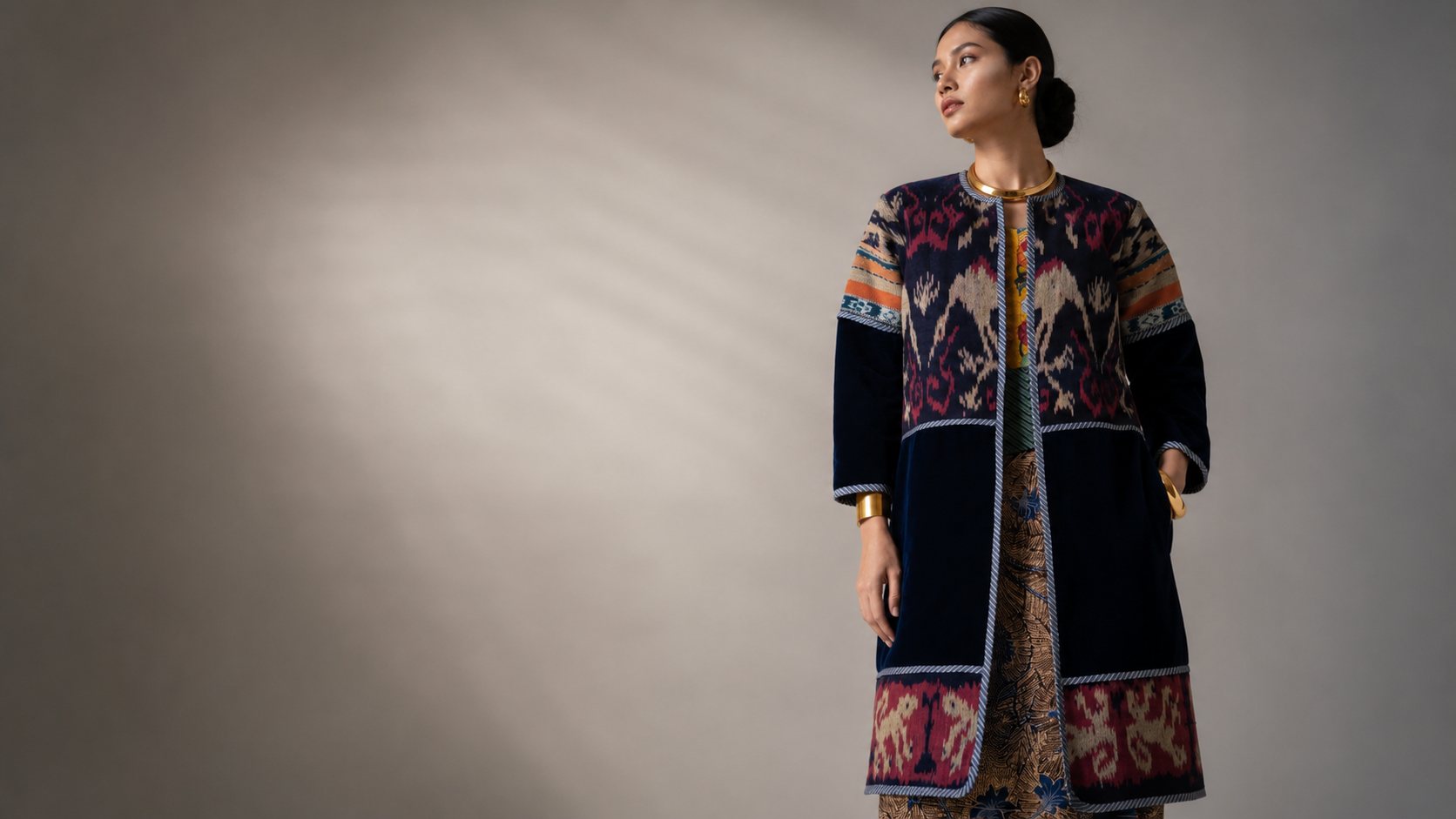 A model in a navy ikat velvet coat in dappled light